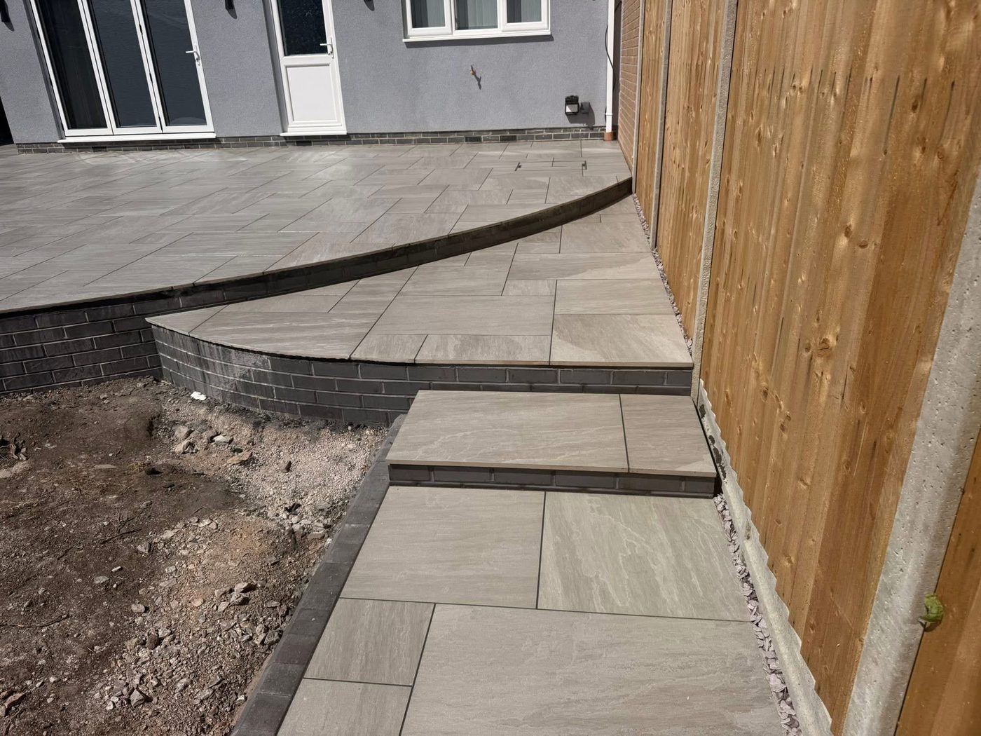 The same garden with a raised porcelain patio and curved steps