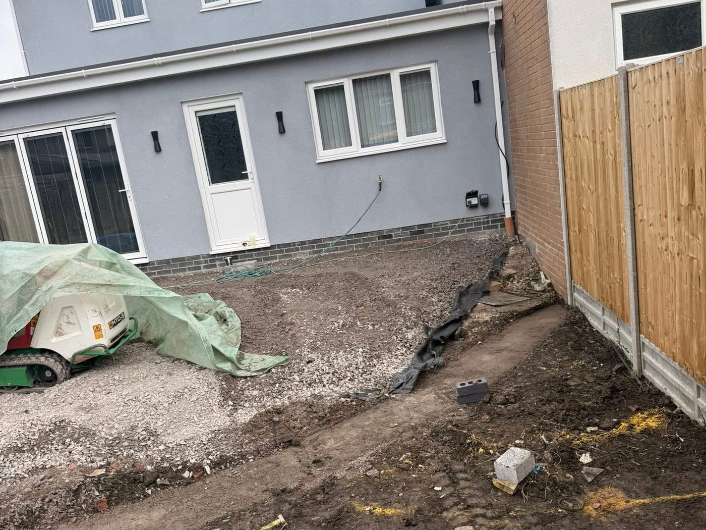 Bare dug out ground behind a rendered house before the patio went down