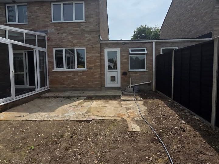 Bare earth and broken slabs behind a brick house before the block paved patio went down