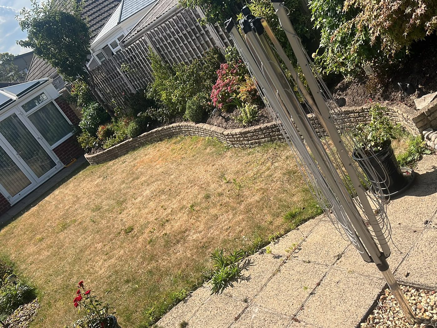 Patchy dry lawn in a bungalow garden before the artificial grass went down
