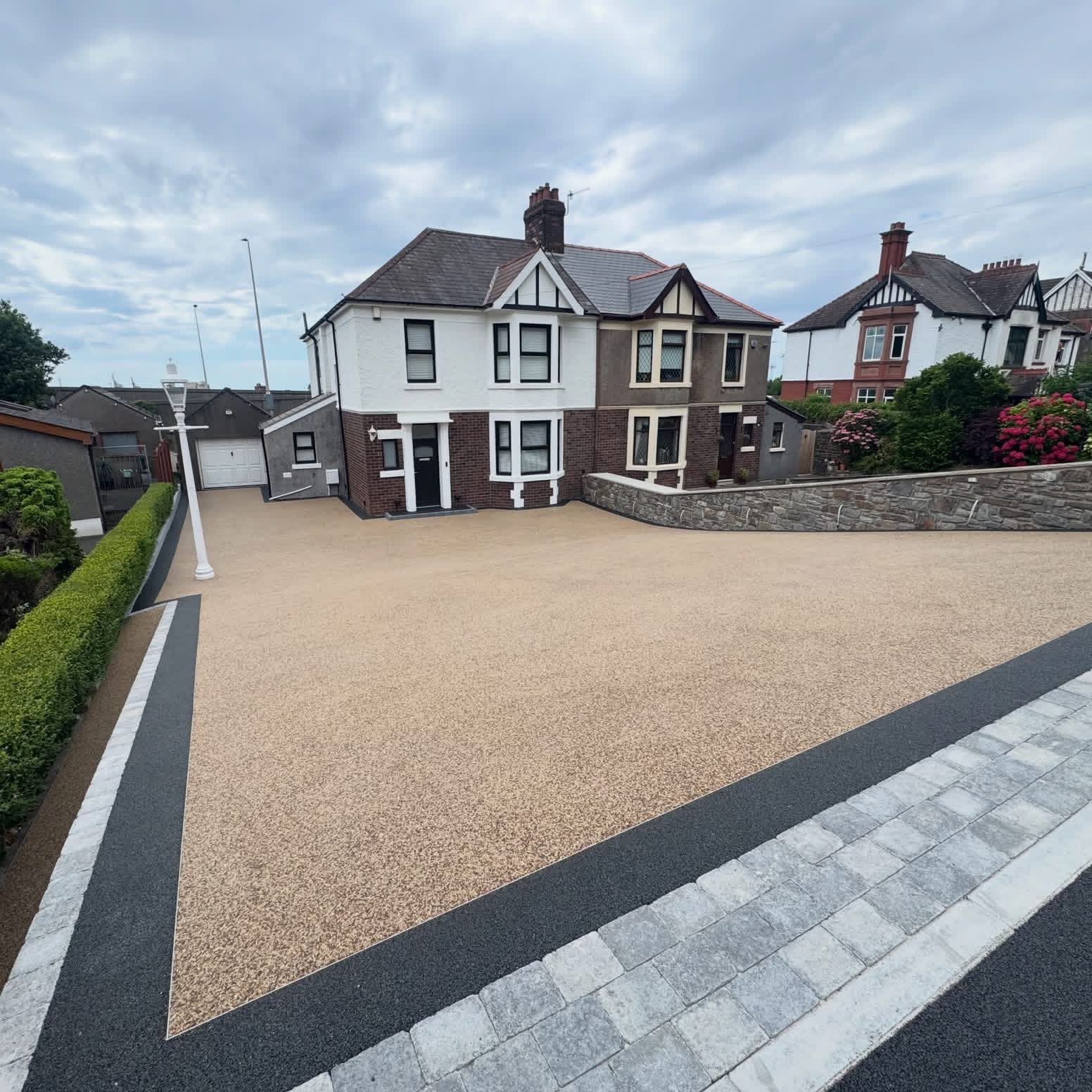 Buff resin bound driveway with charcoal and granite block borders on a semi detached house
