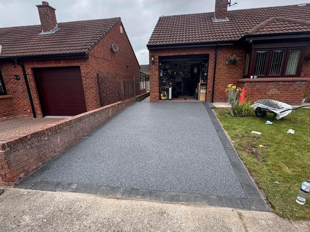 Grey resin bound driveway with a charcoal block edge on a bungalow