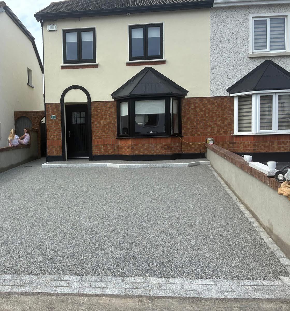 Silver grey resin bound driveway with a granite sett border on a semi detached house