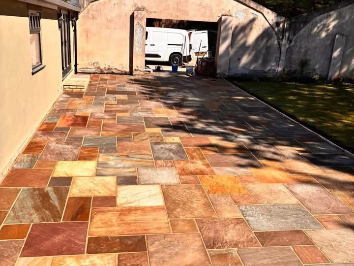 Multi coloured Indian sandstone paving laid up to a garage