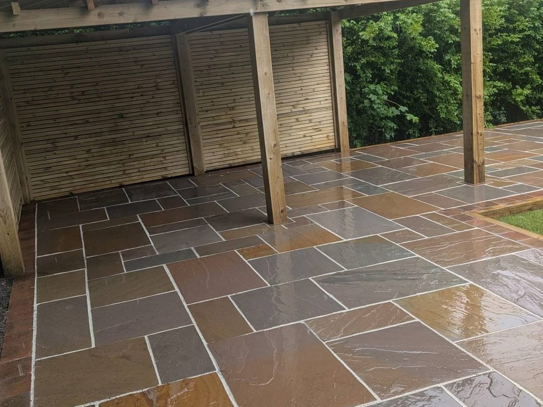 Indian sandstone patio laid under a timber pergola